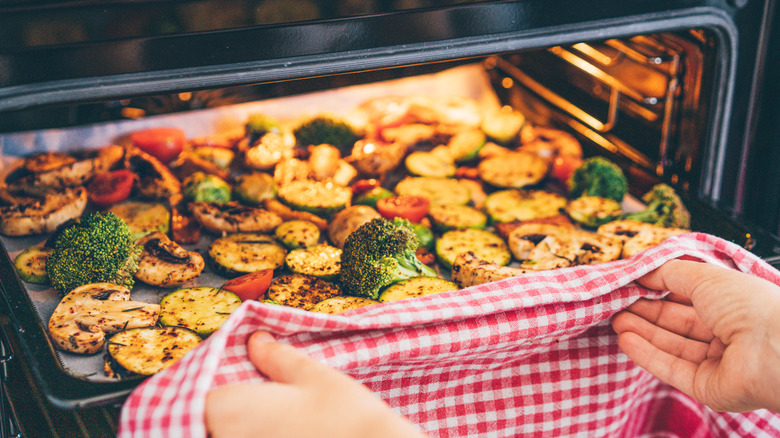 cook pulling roasted vegetables from oven