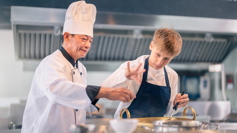 old school chef teaching a young apprentice