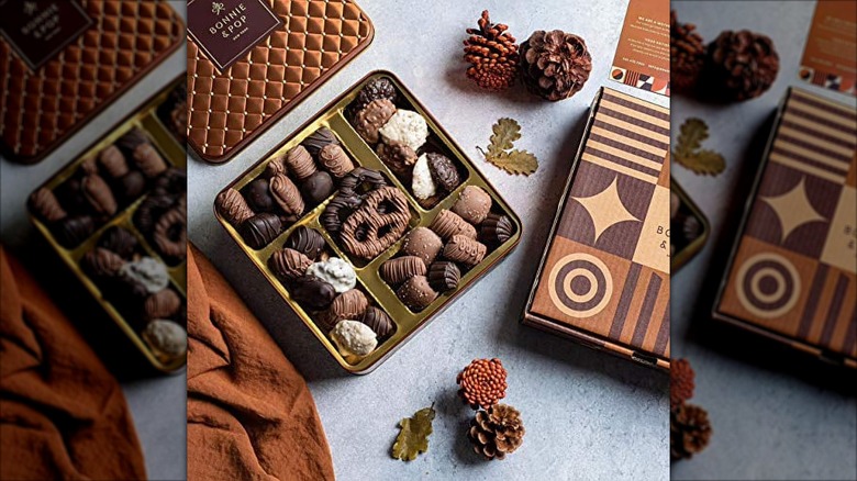 An open Bonnie and Pop Chocolate Gift Tin displays the treats inside and is surrounded by decorative elements.