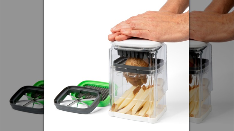 Hands press a potato into a Prep Solutions 3-in-1 Deluxe French Fry Cutter.