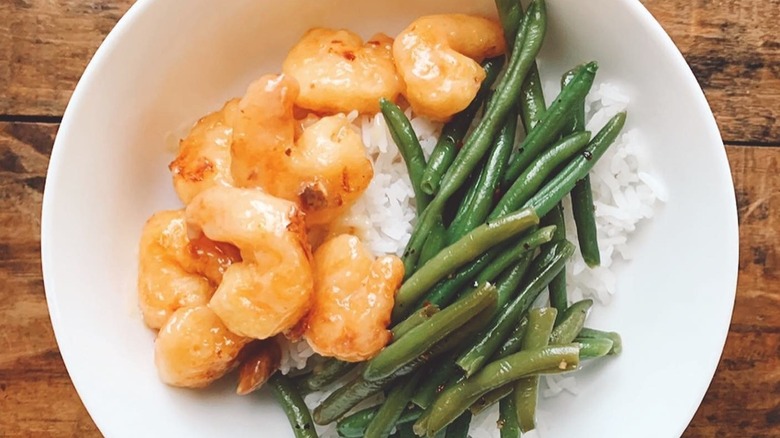A serving of Trader Joe's Honey Walnut Shrimp on top of some white rice with green beans.