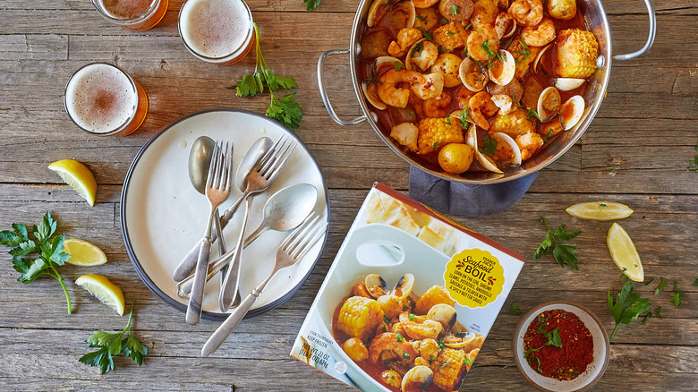 A Trader Joe's Seafood Boil package sits on a wooden surface near a pan of prepared product.