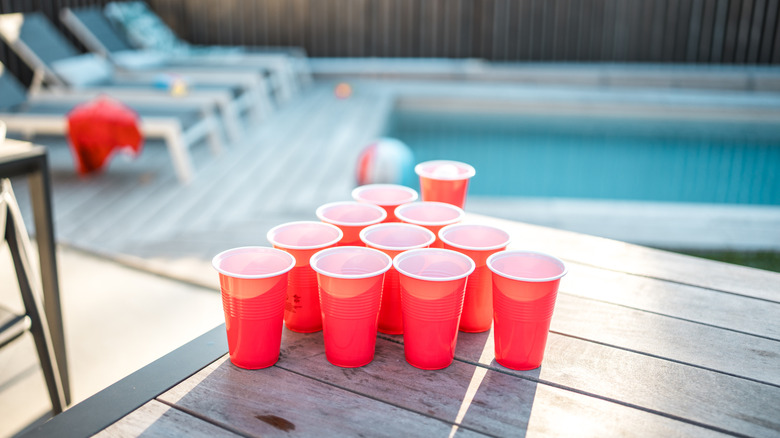 Red Solo cups on a deck with a pool and loungers in the background
