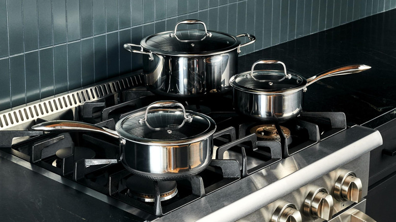 A HexClad 6-piece saucepan set sits on a gas stove