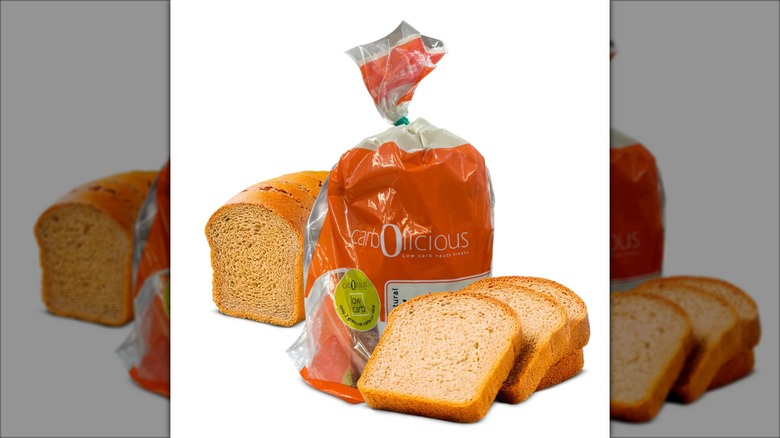 A loaf and slices of Carbolicious All Natural Low-Carb Bread sit adjacent to a bread package.