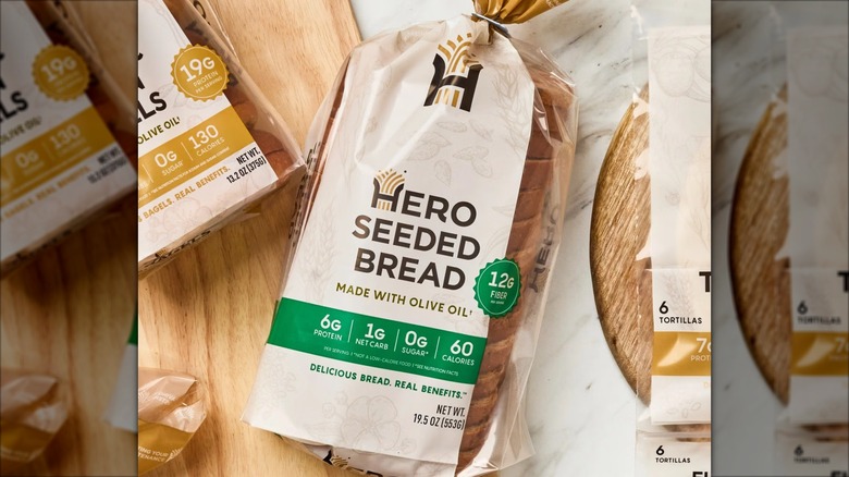 A loaf of Hero Seeded Bread sits against wooden and marble surfaces