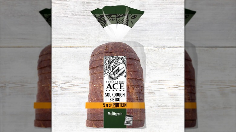 A package of ACE Bakery Multigrain Protein Sourdough Bistro Loaf against a white, wood-grained background.