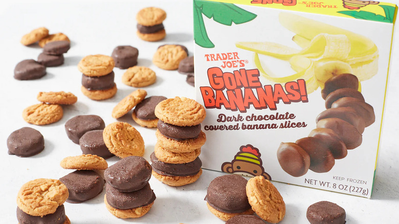 A box of Trader Joe's Gone Bananas! frozen treats sits next to individual chocolate-covered bananas slices stacked up with bite-sized cookies.