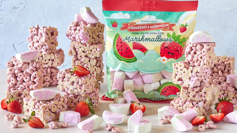A bag of Trader Joe's Strawberry & Watermelon Marshmallows surrounded by marshmallows, strawberries, and cereal treats made using the marshmallows.