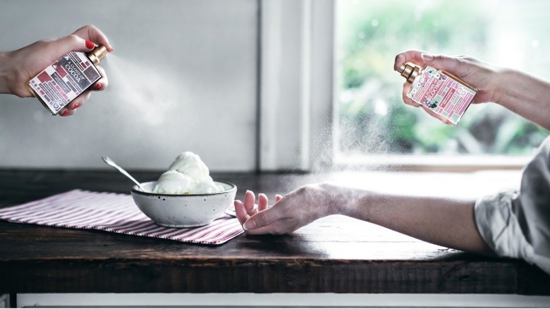 Hands spritzing perfume on ice cream