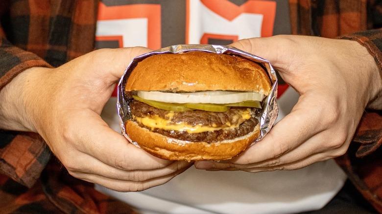 Hands hold a burger from Swensons.