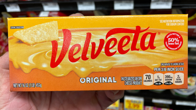 A hand holds a Velveeta cheese block at the store