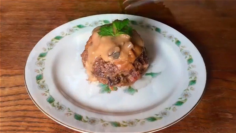 A stuffed burger bundle covered with creamy, light brown sauce and parsley.