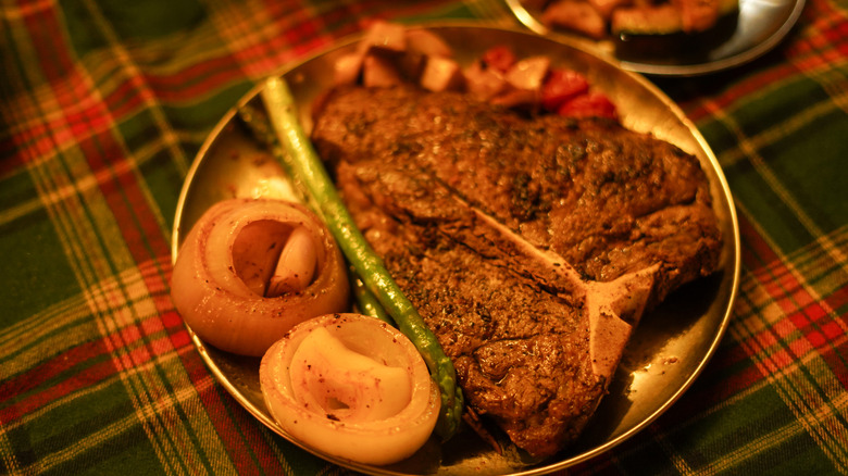 Steak with asparagus and onions on a metal plate