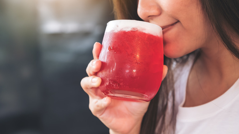 woman sampling a pink cocktail