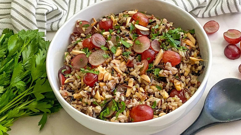 Large white bowl of wild rice pilaf with halved red grapes
