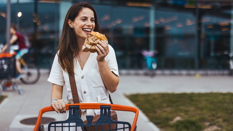 Woman eating with grocery cart
