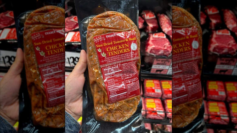 A hand holds up a package of Trader Joe's Sun-Dried Tomato & Basil Chicken Tenders.