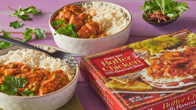 A box of Trader Joe's Butter Chicken with Basmati Rice next to two bowls filled with the cooked product.