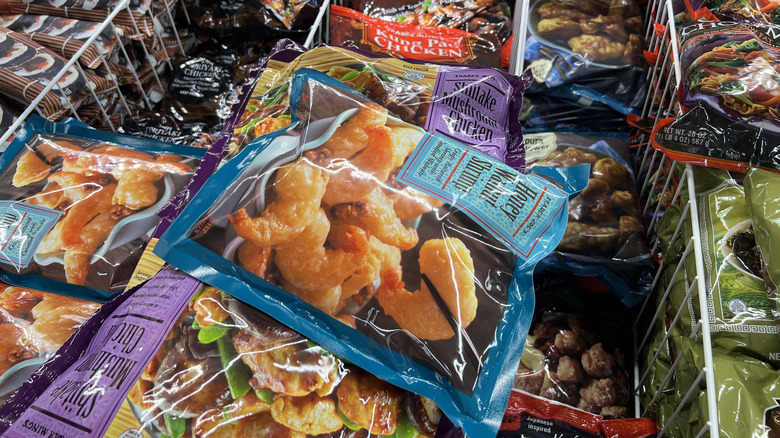A package of frozen shrimp sits atop other products in a Trader Joe's freezer case.