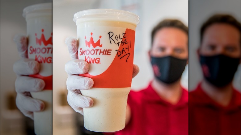 A Smoothie King worker holds up a smoothie