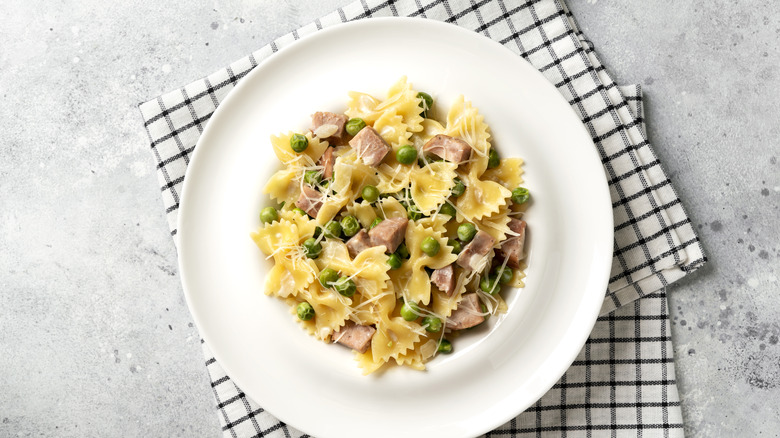 White pot of bowtie pasta with ham and peas