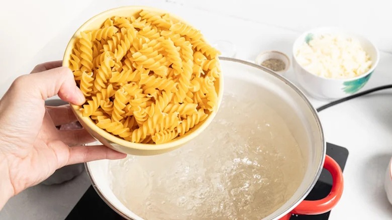 dried rotini going into boiling water