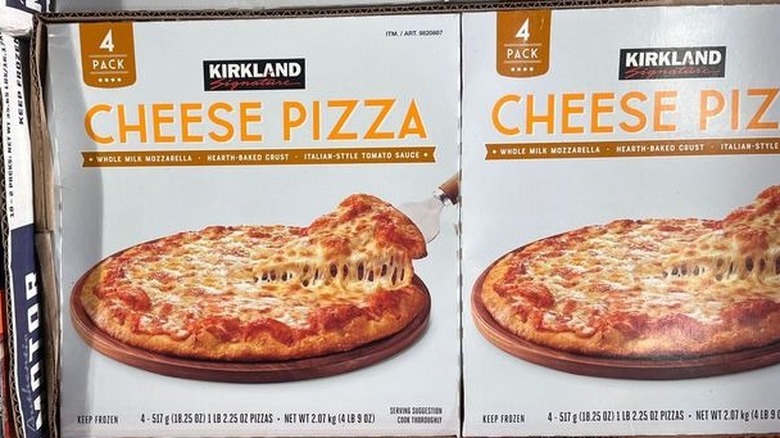 Boxes of Kirkland Signature frozen Cheese Pizza are displayed in a freezer.