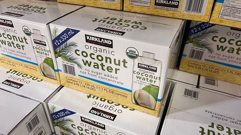Stacked cases of Kirkland Signature Organic Coconut Water are shown in store.
