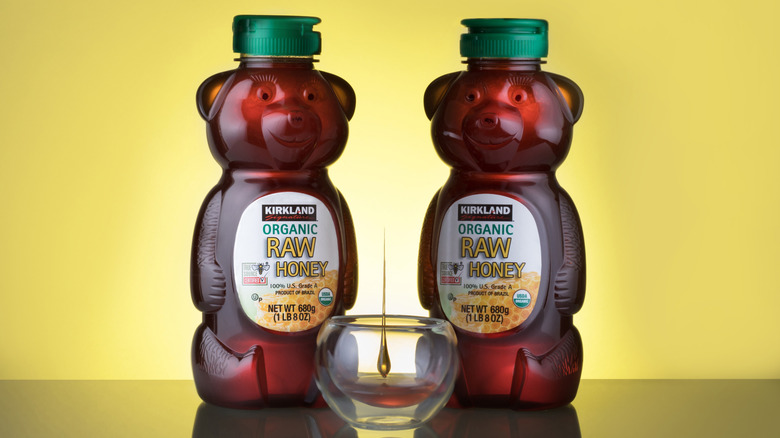 Two Kirkland Signature Organic Raw Honey bears are stood up next to each other.