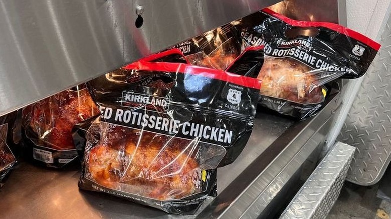 Kirkland Signature Rotisserie Chickens are displayed under heat lamps in store.
