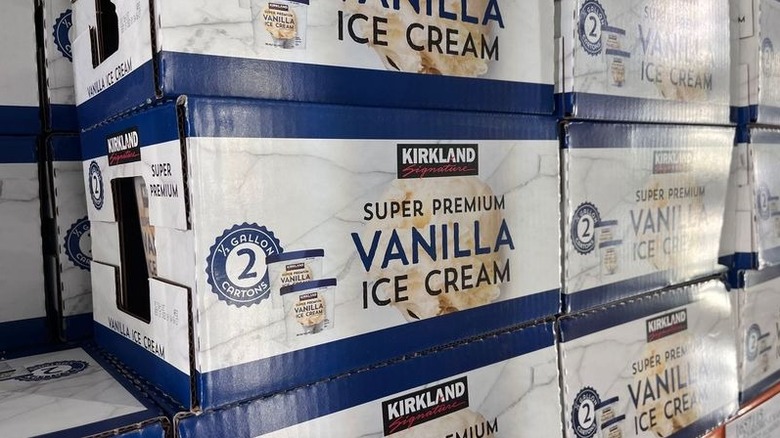 Boxes of Kirkland Signature Super Premium Vanilla Ice Cream are stacked in a freezer.
