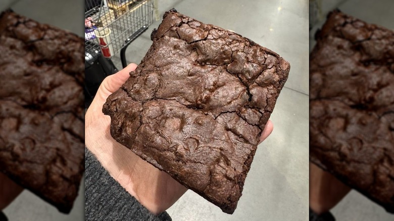 Hand holding a large Costco Australia food court brownie.