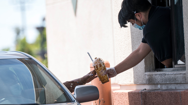 Barista hands drink to driver