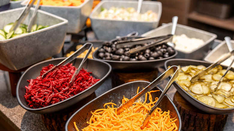 Bowls with a variety of toppings for a hot dog.