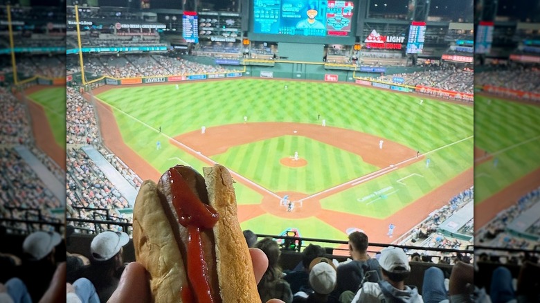 A hand holds a hot dog at Chase Field