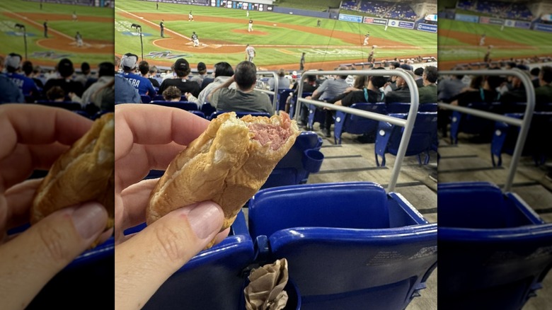 A hand holds out a bitten hot dog at loanDepot Park.