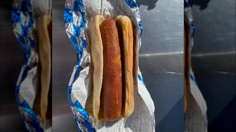 A hands holds out a hot dog from Oracle Park.