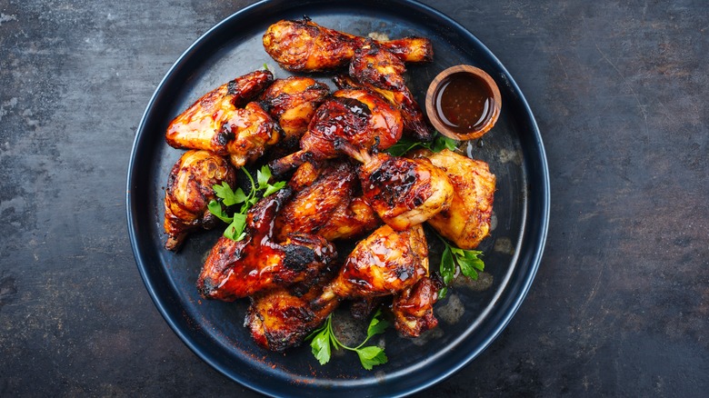 A serving of sauced chicken wings on a black plate with cilantro
