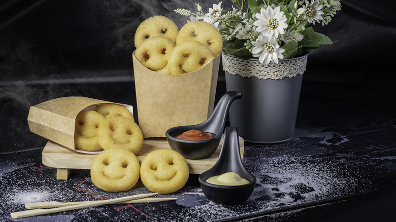 Paper sleeves of potato smiles with dipping sauces on side