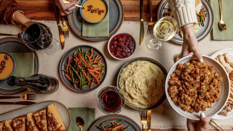 Diners pass plates around a table set with Cooper's Hawk Thanksgiving dishes