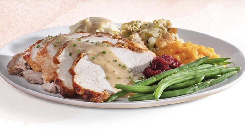 Turkey platter surrounded by vegetables, potatoes, and stuffing