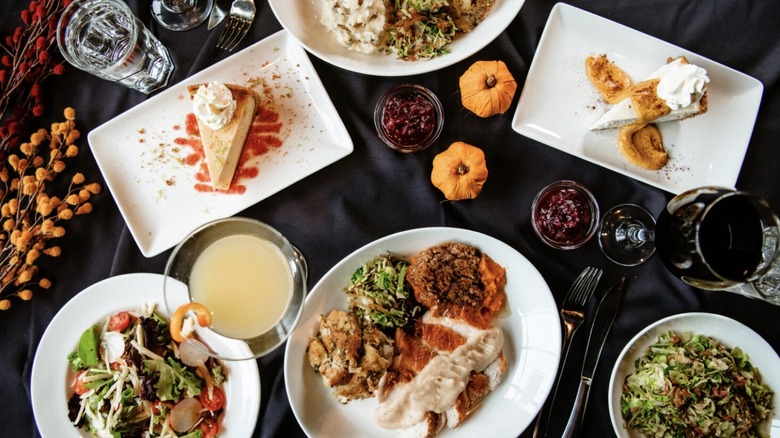 Thanksgiving plates with salads and desserts on a black tablecloth