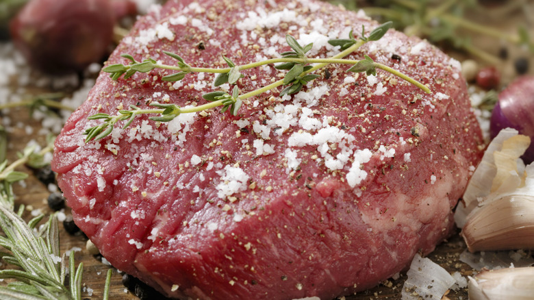 kosher salt on raw filet with fresh herbs, shallots, and garlic