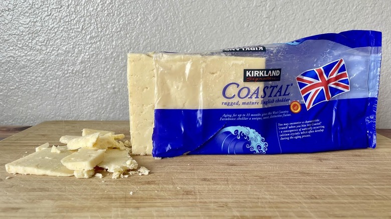 Block and crumbly slices of Kirkland Signature Coastal Rugged Mature English Cheddar on a cutting board