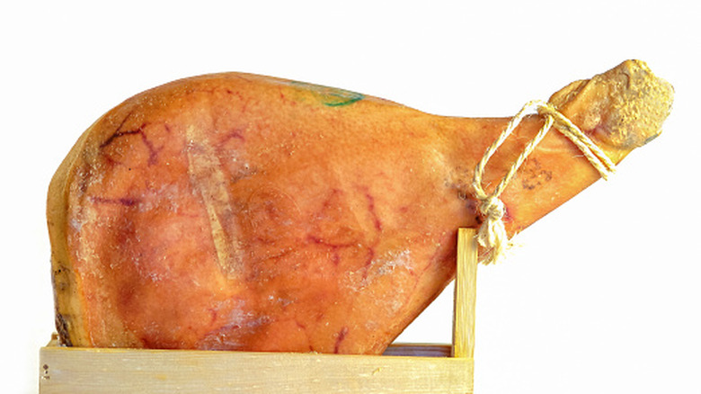 a whole leg of Italian cured ham against a white background