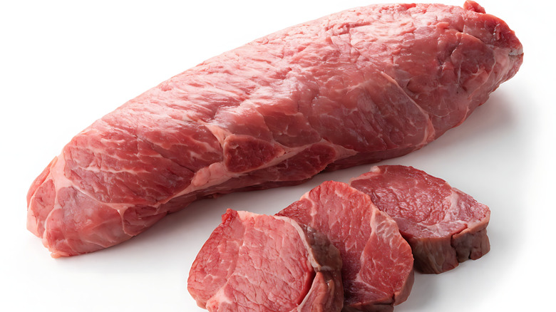 a beef tenderloin with three portioned steaks against a white background
