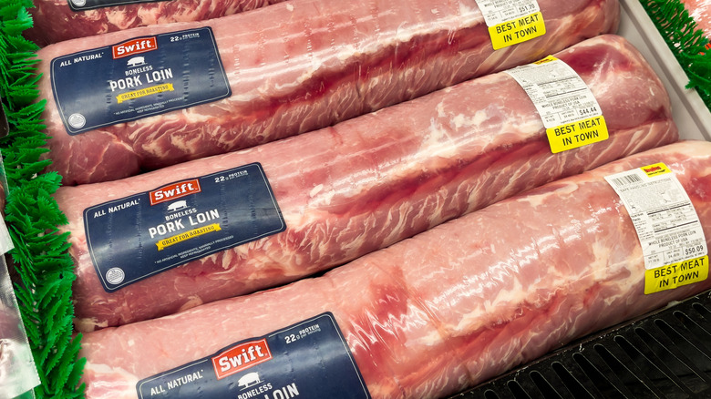a selection of plastic wrapped whole pork loins for sale at a grocery store