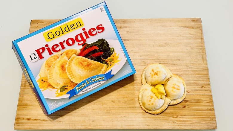 Box of Golden Gourmet Potato & Cheddar Pierogies with cooked ones on side