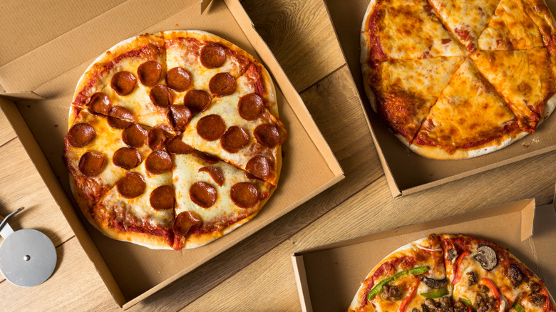 Various pizzas shown in delivery boxes.